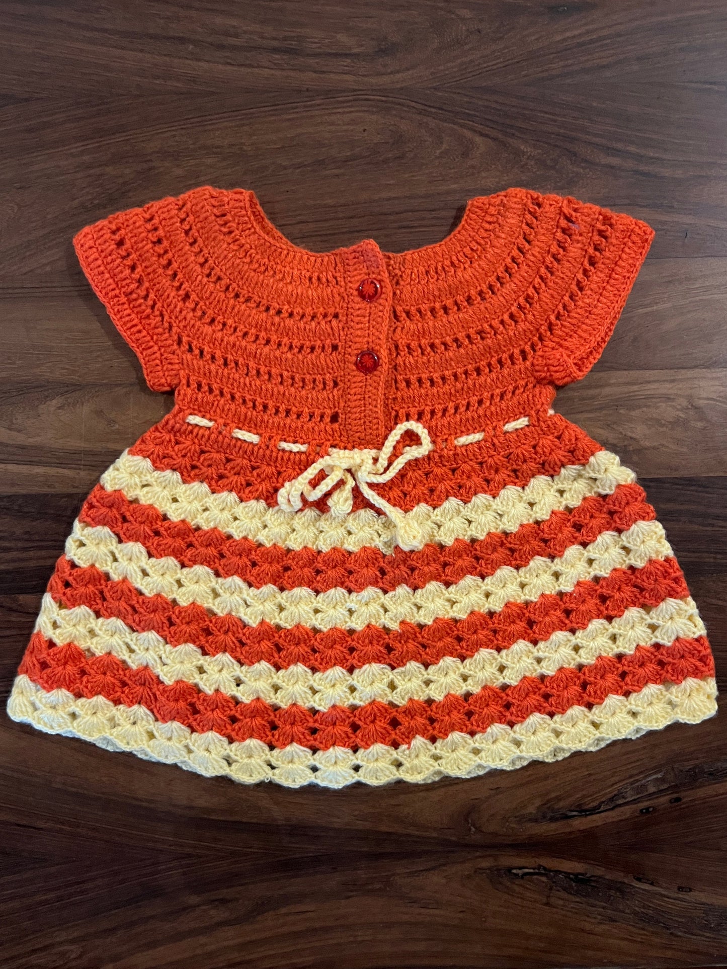Handmade orange and cream crochet baby frock by Madhuri Woollens