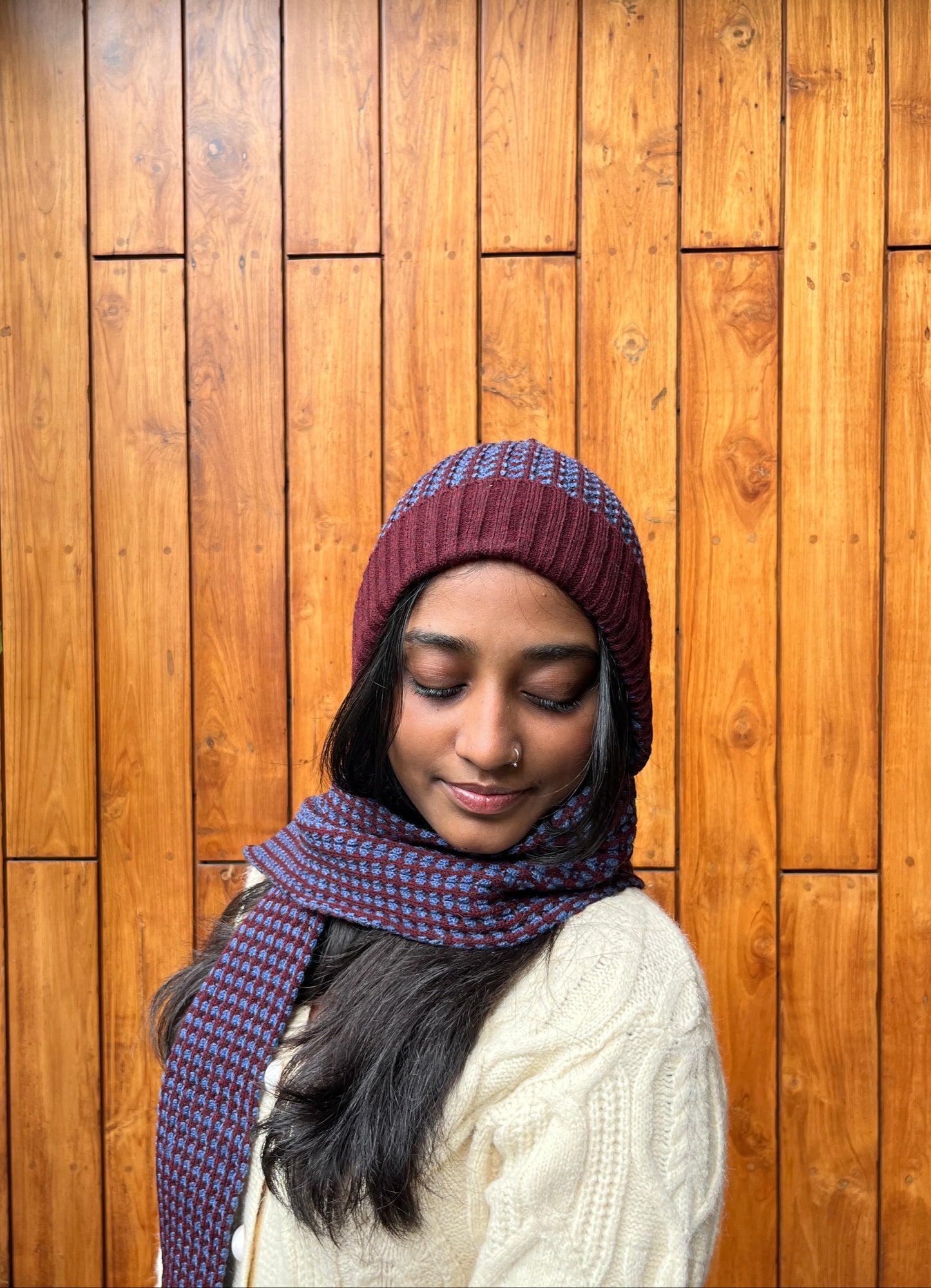 Woman wearing rust and navy blue woollen cap with attached scarf – Madhuri Woollens
